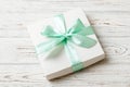 wrapped Christmas or other holiday handmade present in white paper with green ribbon on colored background. Present box Royalty Free Stock Photo