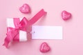 Wrapped gift box with pink bow, blank tag and glitter hearts Royalty Free Stock Photo
