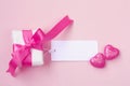 Wrapped gift box with pink bow, blank tag and two hearts Royalty Free Stock Photo