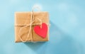 wrapped gift box with red heart shped tag over blue background, space for text, ad, promo, holidays greeting and Royalty Free Stock Photo