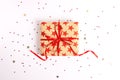 Wrapped gift box with red ribbon and bow on white wooden background. Royalty Free Stock Photo