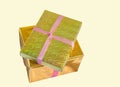 Wrapped in gold foil, two gift boxes tied with red ribbon and stacked, isolated on a yellow background Royalty Free Stock Photo