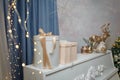 Wrapped Merry Christmas gifts and golden shiny reindeer, winter bird toys on white piano. Golden garland lights bokeh Royalty Free Stock Photo