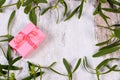 Wrapped pink gift for Christmas and frame of mistletoe on old wooden background