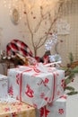 Wrapped present boxes on blurry Christmas background with garlands boke. White paper with red ribbon and bow, Christmas pattern Royalty Free Stock Photo