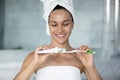 Happy young hispanic woman applying toothpaste on brush.