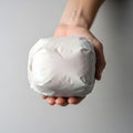 Wrapped White Cube Held in Hand on Plain Background Royalty Free Stock Photo