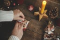 Wrapping christmas gift. Hands wrapping gift box in festive craft red paper on rustic wooden table with candle, scissors and