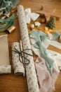 Wrapping christmas gift. Stylish festive wrapping paper, scissors, ribbons and modern decorations on wooden table, top view. Merry