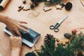 Wrapping christmas gifts concept. Hands wrapping christmas gift in black paper and pine branches, cones, gingerbread cookies, Royalty Free Stock Photo