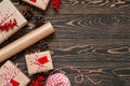 Wrapping christmas presents. Flat lay with decorated gifts, twine string, craft paper and pine cones on the brown wooden backgroun