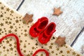 Wrapping first gift for baby for christmas , red little shoes packed in brown paper with gold stars and satin ribbon Royalty Free Stock Photo