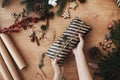 Wrapping rustic christmas present, flat lay. Hands wrapping christmas gift in stylish striped paper and pine branches, cones,