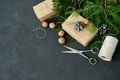 Wrapping rustic eco Christmas packages with brown paper, string and natural fir branches on dark background