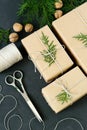 Wrapping rustic eco Christmas packages with brown paper, string and natural fir branches on dark background
