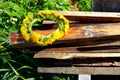 A wreath of dandelions lies on wooden planks. A braided wreath of yellow flowers. Royalty Free Stock Photo