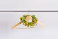 A wreath of flowers hung on a wooden hanger on a white background. Spring, wedding preparations, flowers to decorate the bride`s