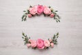 Wreath made of beautiful rose flowers and green leaves on white wooden background, flat lay. Space for text Royalty Free Stock Photo