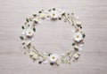 Wreath made of chamomile flowers and green leaves on white wooden background, flat lay. Space for text Royalty Free Stock Photo