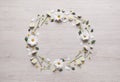 Wreath made of chamomile flowers and green leaves on white wooden background, flat lay. Space for text Royalty Free Stock Photo