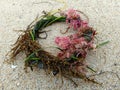Wreath Made of Green, Brown and Pink Sea weeds on a sandy beach in California