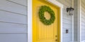 Wreath on yellow front door and a lamp on a wall