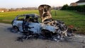 Wreck of a burnt car in the street in the countryside