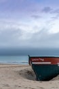 Wreck of an old wooden rowboat buried in the sand with an overcast sky and ocean behind