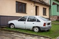 Wreck of white Opel Kadett car parked in front of the house