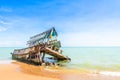 The wreckage of the fishing boat is beached with blue sea and the blue sky as background.location Satheep Thailand