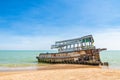 The wreckage of the fishing boat is beached with blue sea and the blue sky as background.location Satheep Thailand