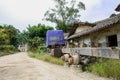 Wreckage of truck before weedy ruins of old Chinese houses