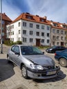 Wrecked damaged small car Peugeot 206 on street.