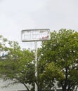Wrecked sign on pole after high winds stands above trees - selective focus