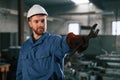 Wrench in the hand. Factory worker in blue uniform is indoors