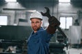 Wrench in the hand. Factory worker in blue uniform is indoors