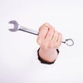 A wrench in the hand of a girl. Symbol of hard work, feminism and labor day. Isolate on white background