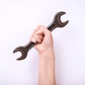 A wrench in the hand of a girl. Symbol of hard work, feminism and labor day. Isolate on white background