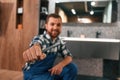 With wrench in hand. Plumber in blue uniform is at work in the bathroom Royalty Free Stock Photo