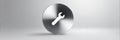 Wrench Icon on Round Brushed Metal Disc, Standing on a Gray Background, Represents Repair or Maintenance Royalty Free Stock Photo