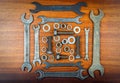 Wrenches, bolts, nuts and washers squared on a brown wood texture background