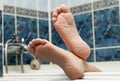 Wrinkled bare feet coming out from a bathtub. Young person getting a bath feet close-up indoor in bathroom interrior photo