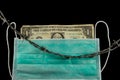 Wrinkled Dollar Bill behind a medical face mask with barbed wire laying on top to confine Royalty Free Stock Photo