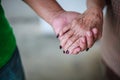 Wrinkled elderly woman`s hand holding to young man`s hand, walking in shopping mall park. Family Relation, Health, Help, Support Royalty Free Stock Photo