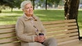 Wrinkled face of 60s happy elderly woman outdoors in park looking aside having wide smile, dental implants and Royalty Free Stock Photo