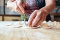 Wrinkled grandmothers hands putting filling in dough