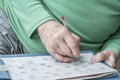 Wrinkled hand of old person solving crossword puzzle Royalty Free Stock Photo