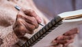 wrinkled hands for elderly person writing notes on his note book Royalty Free Stock Photo