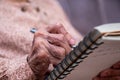 wrinkled hands for elderly person writing notes on here note book in living room Royalty Free Stock Photo