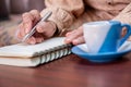 wrinkled hands for elderly person writing notes on his note book while drinking coffee Royalty Free Stock Photo